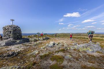 Eine große Steinwarte und Wanderer auf dem höchsten Punkt des Bjørgovarden