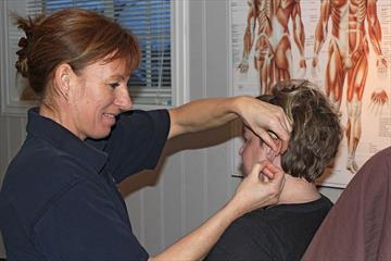 A therapist is giving acupuncture to a patient.