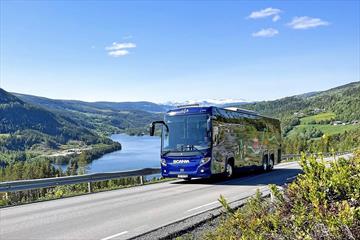 Buss på vei med fin utsikt mot vann og fjell