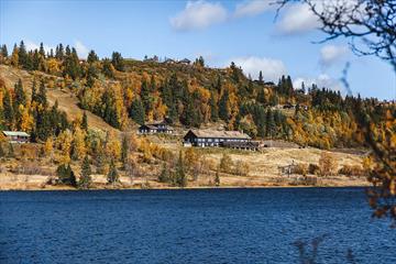 Gamlestølen ligger flott til med fiskevann rett nedenfor, og fjellterreng bak fjellstuen.