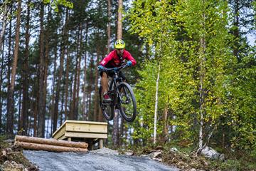 A cyclist jumping over an obstacle in  the terrain cycling area at Leira