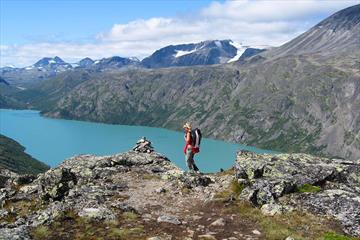 Dame på fjelltur over en fjellrygg over bregrønt vann