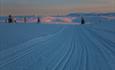 Langrennsløyper i fjellterreng og solnedgang