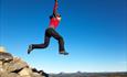 A woman jumps from a cairn