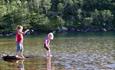 Kinder angeln mit Blinker in einer flachen Flusspartie an einem schönen Sommertag