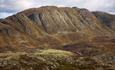 The summit point of Horntinden is located on a long mountain ridge, showing its steep flank to the photographer, while the trail leads up on the less