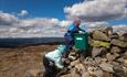 Two small children climb on a summit cairn in open high country.