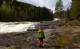 A childs on naked rock next to a river