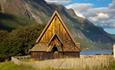 Øye stavkirke om sommeren. Innsjø og fjell i bakgrunnen.