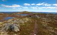 A trail trough open high country past a couple of small lakes.