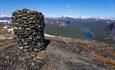 The summit cairn on Skjøld is large and built with great care. The view to the valley below with a lake and high mountains on the horizon is breathtak