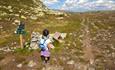 A little girl studies a signpost along the tail in the mountains.