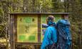 A man rading about the battle at Gråbeinhølet during WWII on an information board along the trail to Bagnsbergatn.