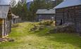 The sun is shining on the grass courtyard between the old buidings and walls at Bagnsbergatn.