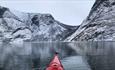 Kajakk med høye snødekte fjell foran