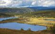 Idyllic surroundings with farm roads, cabins and lakes at Nordre Fjellstølen. In the background the Makalaus mountain massif with its steep hillsides