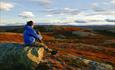 A woman sits on a rock in the autumn-coloured mountains