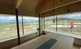 A barren alpine high mountain plateau with peaks in teh background is seen through the panoramic windows of Flye1389