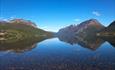 On the shore of Lake Vangsmjøse. The water is crystal clear and calm like a mirror. On the far side of the lake, Skutshorn is the most dominant mounta