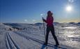 A young girl on cross-country skies in the mountains against the sun