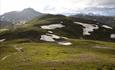 Sti gjennom grønt fjellandskap med fjell i bakgrunnen