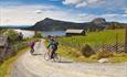 Cyclists at Juvike, an idyllic farming village. In the backgroundt, Lake Mellsenn and the mountains Skarvemellen (left) and Rundemellen (right) can be