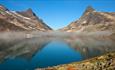 Utsikt mot vann og spisse tinder i Jotunheimen