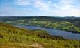 View from Jutulen towards a lake, a country village with many small green fields and forested hillsides.