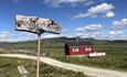 Red summer farm hut and a wooden sign at Storeskag