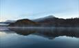 Nøsakampen and its reflection seen from Helin in a kayak before sunrise. Morning mist lies over the water surface, and the mountains are autumn-colour