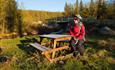 A cyclist taking a break at a small stream where there is a nice bench.