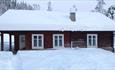 Eine altes Blockhaus auf einem Hof im Tiefschnee.