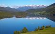 Aussicht über den Slidrefjorden von Røn. Im Hintergrund links sieht man den Hugakollen, und der Horizont wird von dem mächtigen Bergmassiv des Vennisfjellets dominiert.