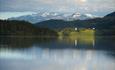 Blick über den See Slidrefjorden vom Rastplatz an der E16 bei Lomen aus. Im Hintergrund sieht man die Kirche von Lomen und das Bergmassiv des Vennisfjellet.