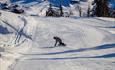 Snowboarder at Stavadalen Skisenter with a view downhill to the bottom of the slope.