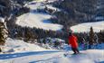 Skifahrer in roter Jacke im Stavadalen Skisenter mit Aussicht zum Talende der Piste.