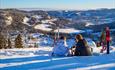 Zwei Skifahrerinnen genießen eine Pause in der Piste mit einer großartigen Aussicht.