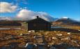 Sulebu en fin høstdag. Hytta ligger rett ved et lite vann, og fjelltoppene troner i bakgrunnen