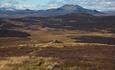 Vid og åpen lavfjellandskap med utsikt mot fjell i det fjerne.