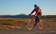 Cyclist at Nørdre Bjørnhovd on the Tansbergrunden cycling route on a crisp summer morning. Skaget (1685 m.a.s.l.) is seen in the background.