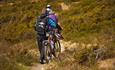 Cyclists walk with their bikes on the trail along Lake Tansbergfjorden.