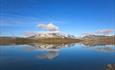 View over a calm lake with pointed peaks mirrowing themselves in the water.