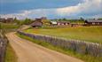 Farm road through a small mountain farm village with huts and green pastures.