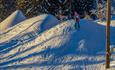 Ein Kind fährt über mehrere Schneehügel im Valdres Alpinsenter i Aurdal.