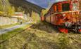 At the old Bjørgo station there are still to grass overgrown train tracks and a red train, consisting of a locomotive and a couple of wagons. A cyclis