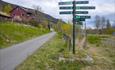 Ein Wegweiser mit vielen Schildern entlang des Radweges auf der Valdresbahntrasse.