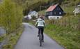 Ein Radler auf der Valdresbahnradweg in einer Siedlung mit Wohnhäusern und Gärten.