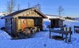 A warming hut with outdoor barbeque in low winter sunlight