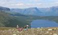 Family with children on a high plateau overlooking a lake and distant mountains.