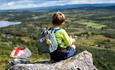 Small kid taking a break on a rock with a painted red T besides him. This indicates that this is along a official DNT path. The view is fantastic.